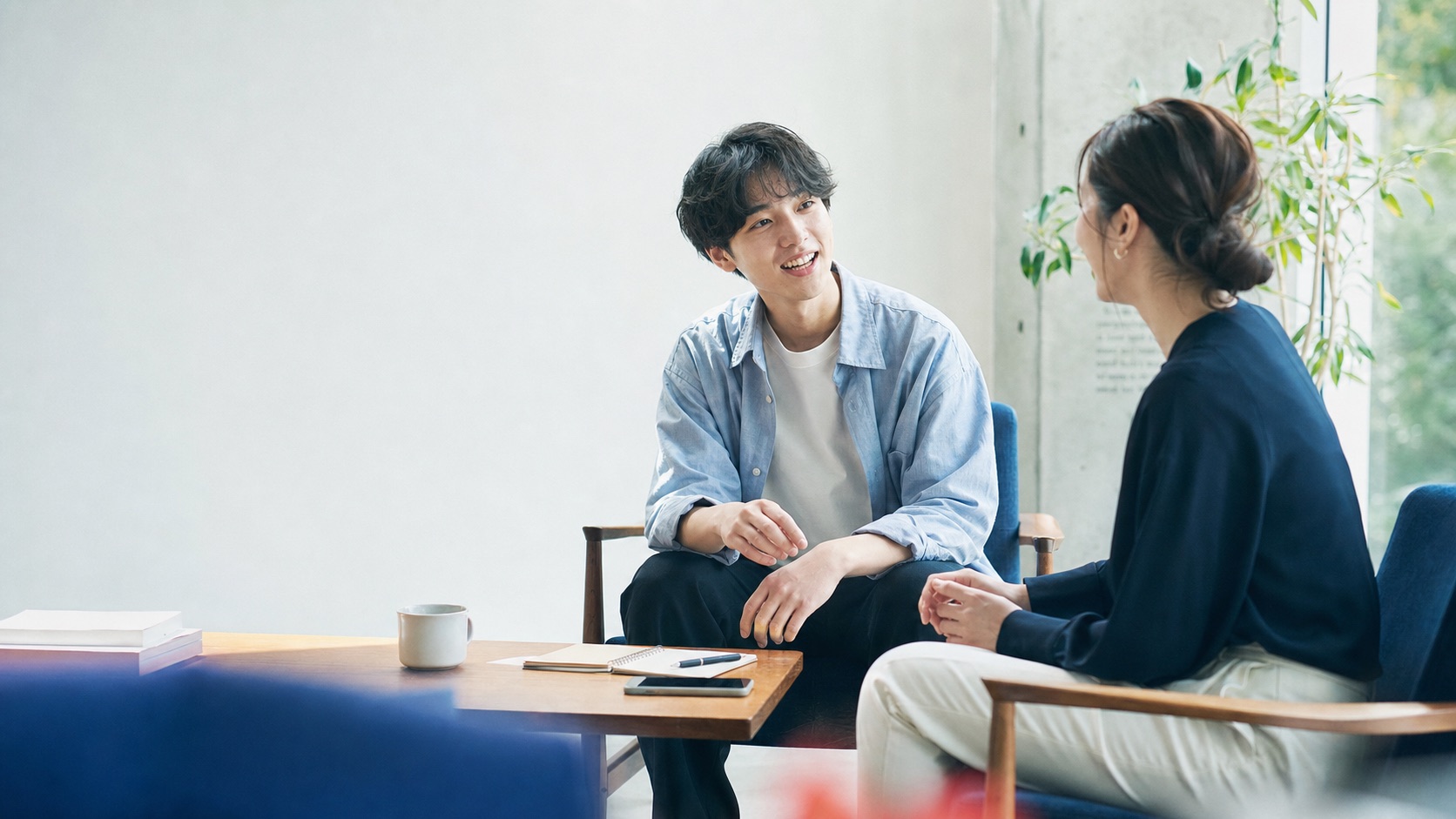 明るい相談スペースでキャリアアドバイザーと話す大学生